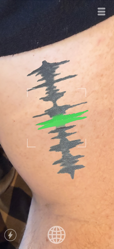 La app Skin Motion escaneando y reproduciendo un tatuaje de onda sonora en la piel de una persona usando realidad aumentada.