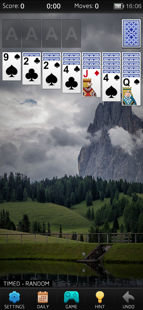 A classic Solitaire game in progress with a beautiful mountain and forest background on a mobile screen