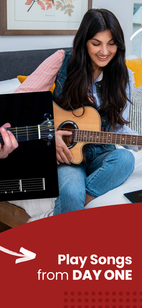 Guitar Lessons - Guitar Tricks - Una mujer sonriendo mientras aprende a tocar canciones de guitarra desde el primer día usando la aplicación Guitar Tricks