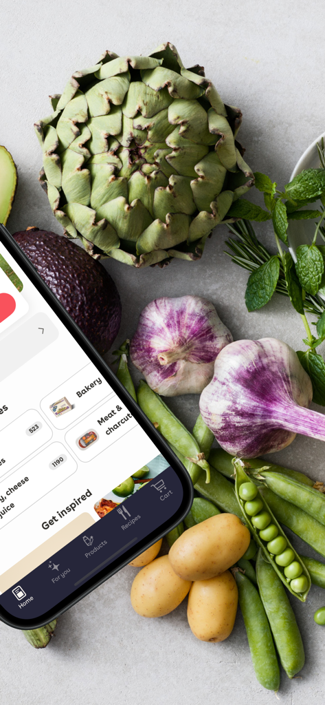 Smartphone displaying the Mathem app interface next to fresh artichoke, garlic, and green peas.