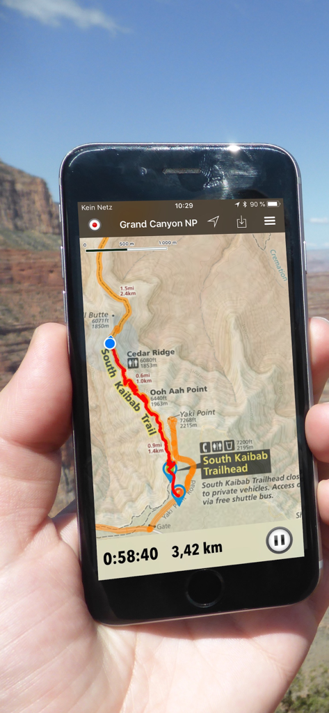 Una mano sosteniendo un smartphone que muestra un mapa topográfico de senderismo con seguimiento GPS para el South Kaibab Trail