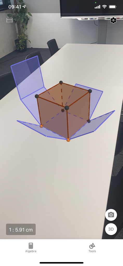 A 3D geometric cube projected onto a physical table using the GeoGebra augmented reality feature.