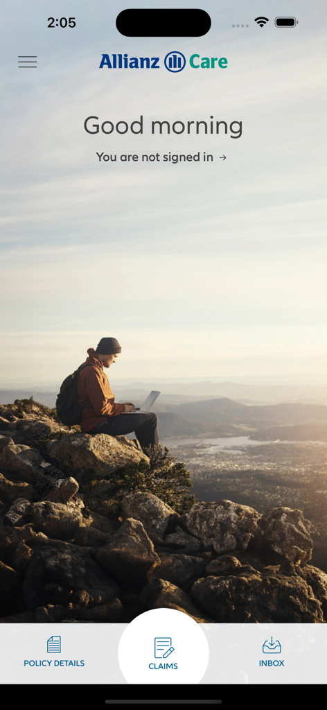 Schermata iniziale dell'App Allianz Care OVHC per Membri che mostra una persona con un laptop su una montagna affacciata su una valle e sull'oceano.