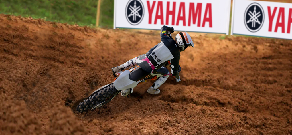 A motocross rider leans into a sharp turn on a realistic dirt track in MX Bikes