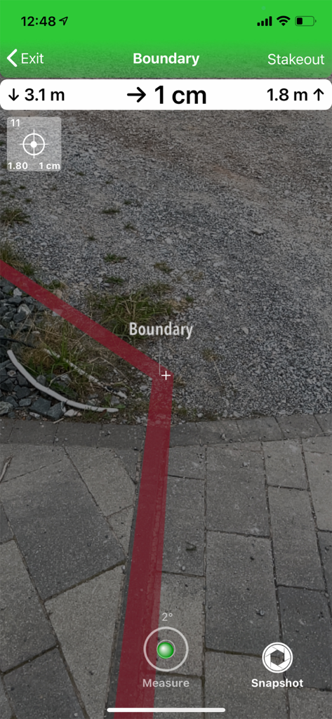 Augmented reality view in GeoAce showing a red boundary line with centimeter accuracy measurements on a stone path.