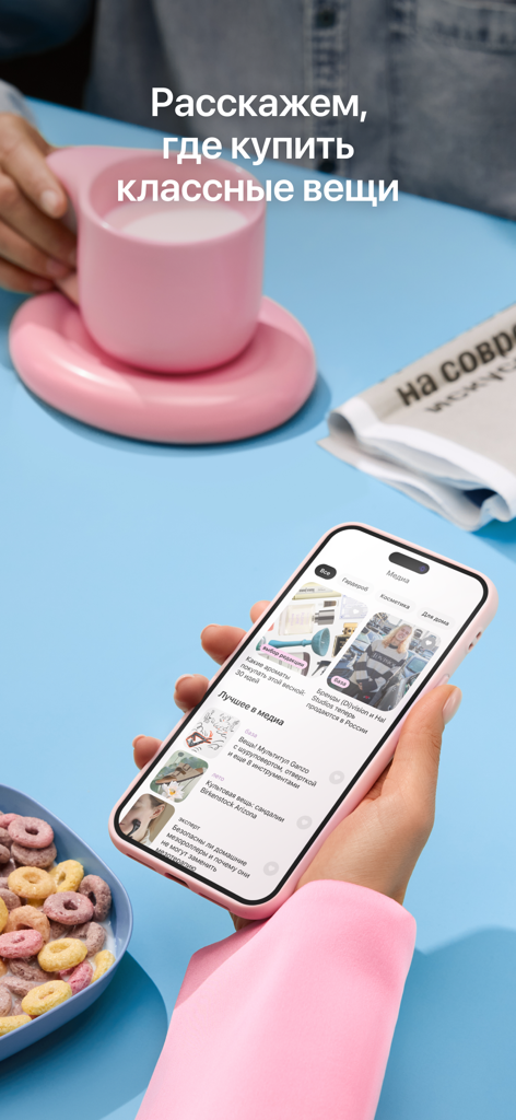 Dolyame - оплата покупок - Mano sosteniendo un smartphone con la aplicación de compras Dolyame abierta junto a una taza rosa y un cuenco de cereales.